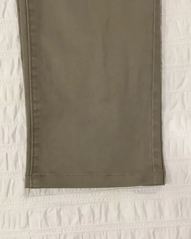 The hem of a pair of olive trousers